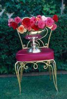 Roses en urne argentée sur une chaise rouge