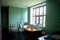 Bain en cuivre sous fenêtre à carreaux de plomb dans la salle de bain traditionnelle