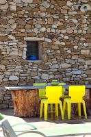 Table et chaises de jardin par mur de pierre rustique