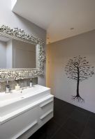 Évier, miroir orné et papier peint mural arbre dans la salle de bain