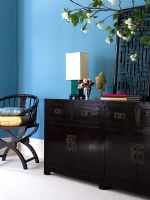 Buffet de style oriental en bois foncé contre le mur bleu