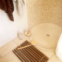 Détail de la base de la douche et du tapis de bain en bois