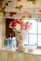 Vase en pierre de fleurs sur le rebord de la fenêtre de la salle de bain