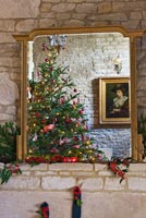 Miroir doré au-dessus d'une cheminée en pierre des Cotswolds à Noël