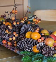 Arrangement de Noël de pommes de pin, fruits et baies sur table en bois
