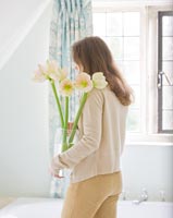Femme tenant un vase d'Amaryllis 'Cherry Blossom' dans la salle de bain