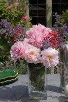Arrangement de roses, menthe et valériane sur table de jardin