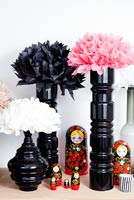Fleurs en papier disposées dans de grands vases noirs