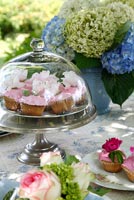 Table de jardin avec cupcakes et hortensias dans un vase