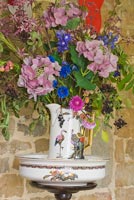 Fleurs colorées, y compris hortensia et bleuets dans une cruche à motifs