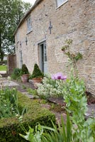 Maison en pierre et bordures de jardin avec coquelicots et valérianes