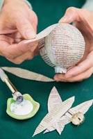 Créez une simple boule de Noël en utilisant du papier journal - en attachant des bandes de papier à la boule