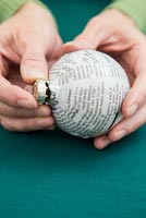 Créez une simple boule de Noël en utilisant du papier journal - remettez le capuchon sur la boule