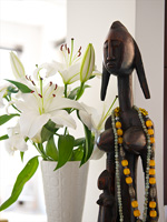 Lys blancs dans un vase rétro à côté de la sculpture tribale