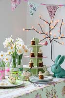 Set de table pour le thé de Pâques avec des fleurs de jonquille en bouteilles