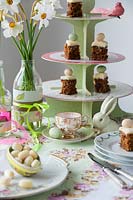Set de table pour le thé de Pâques avec des fleurs de jonquille en bouteilles