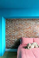 Mur de briques apparentes derrière le lit