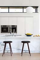 Comptoir de cuisine en marbre avec tabourets de bar en cuir