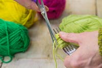 Faire des décorations de pompon de Noël - Utilisez les ciseaux pour couper la laine, laissant un paquet de laine enroulé sur la fourche