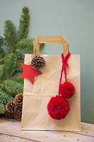 Sac cadeau de Noël en papier marron décoré de pomme de pin, étoile en feutre et pompons en laine