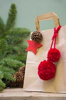 Sac cadeau de Noël en papier marron décoré de pomme de pin, étoile en feutre et pompons en laine