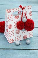 Sac cadeau de Noël décoré de boules argentées et de pompons rouges en laine