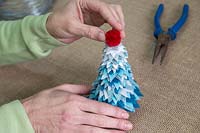 Faire un sapin de Noël en feutre - Ajoutez le pompon au sommet de l'arbre pour le finir