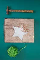 Faire une décoration d'étoile de Noël - Les matériaux requis sont de la laine verte, un marteau, des clous en cuivre, un modèle d'étoile et une section carrée de bois