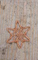 Faire des étoiles en fil de cuivre - décorations finies sur une surface en bois