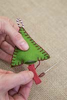 Faire des décorations de Noël en feutre cousu - Coudre un morceau de ficelle colorée à la base de la forme