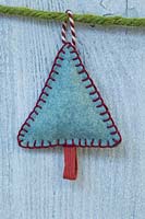 Faire des décorations de Noël en feutre cousu - arbre de Noël miniature en feutre et chaîne décorative, accroché contre un panneau en bois