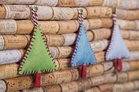 Faire des décorations de Noël en feutre cousu - des sapins de Noël miniatures en feutre et en ficelle décorative, accrochés contre une planche en liège