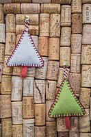 Faire des décorations de Noël en feutre cousu - des sapins de Noël miniatures en feutre et en ficelle décorative, accrochés contre une planche en liège