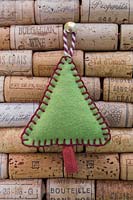 Faire des décorations de Noël en feutre cousu - arbre de Noël miniature en feutre et chaîne décorative, accroché contre une planche en liège
