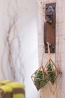 Prismes en cuivre contenant du feuillage de pin, suspendus à la poignée de porte