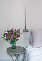 Table de chevet avec vase de fleurs de clématite