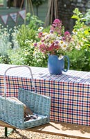 Cruche de Centranthus et Marguerites sur table de jardin