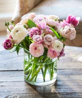 Vase de renoncule, de roses et de fleurs de tulipes sur table basse