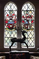 Bougeoir décoratif en métal en forme de coeur bondissant devant le vitrail qui porte les armoiries de Sir Francis Cook - Cothay Manor