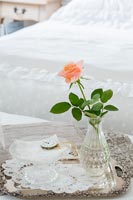 Détail d'une seule rose dans un vase en verre dans une chambre de campagne classique