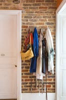 Vêtements et sacs suspendus à des crochets muraux