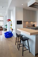 Tabourets de cuisine noirs et sculpture colorée dans un appartement décloisonné moderne