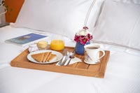 Plateau de petit déjeuner avec des fleurs et du pain grillé sur le lit