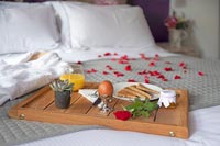 Plateau petit déjeuner sur lit avec pétales de rose et peignoir