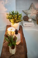 Bois rustique utilisé comme plateau de bain avec des bougies et des plantes