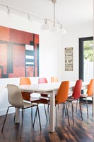 Salle à manger contemporaine avec des chaises de différentes couleurs