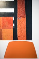 Peinture contemporaine colorée derrière une chaise orange