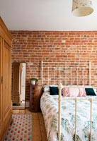 Chambre moderne avec briques apparentes et lit en fer crème
