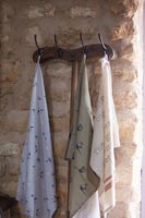Cintre en bois sur mur de pierre avec une variété de foulards en soie