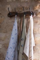 Cintre en bois sur mur de pierre avec une variété de foulards en soie